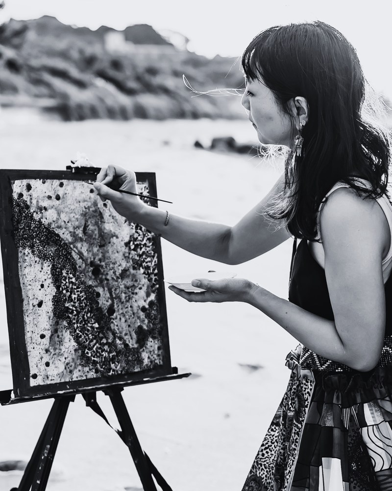 Konatsu Ishijima painting at an easel on the beach in Itoshima